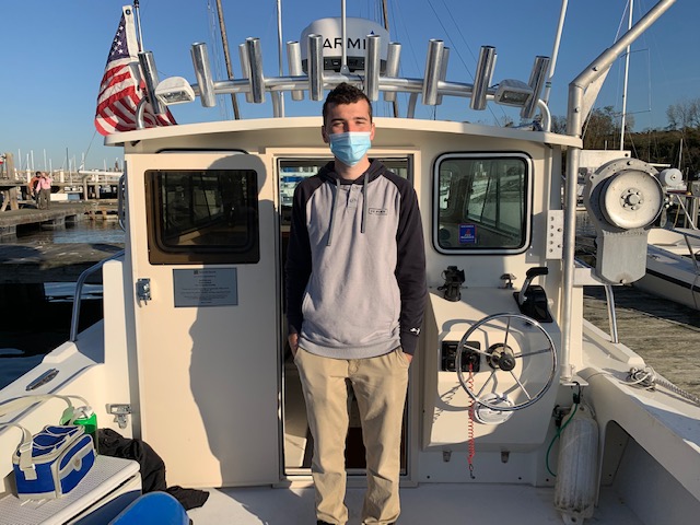 Student standing on a boat while masked.