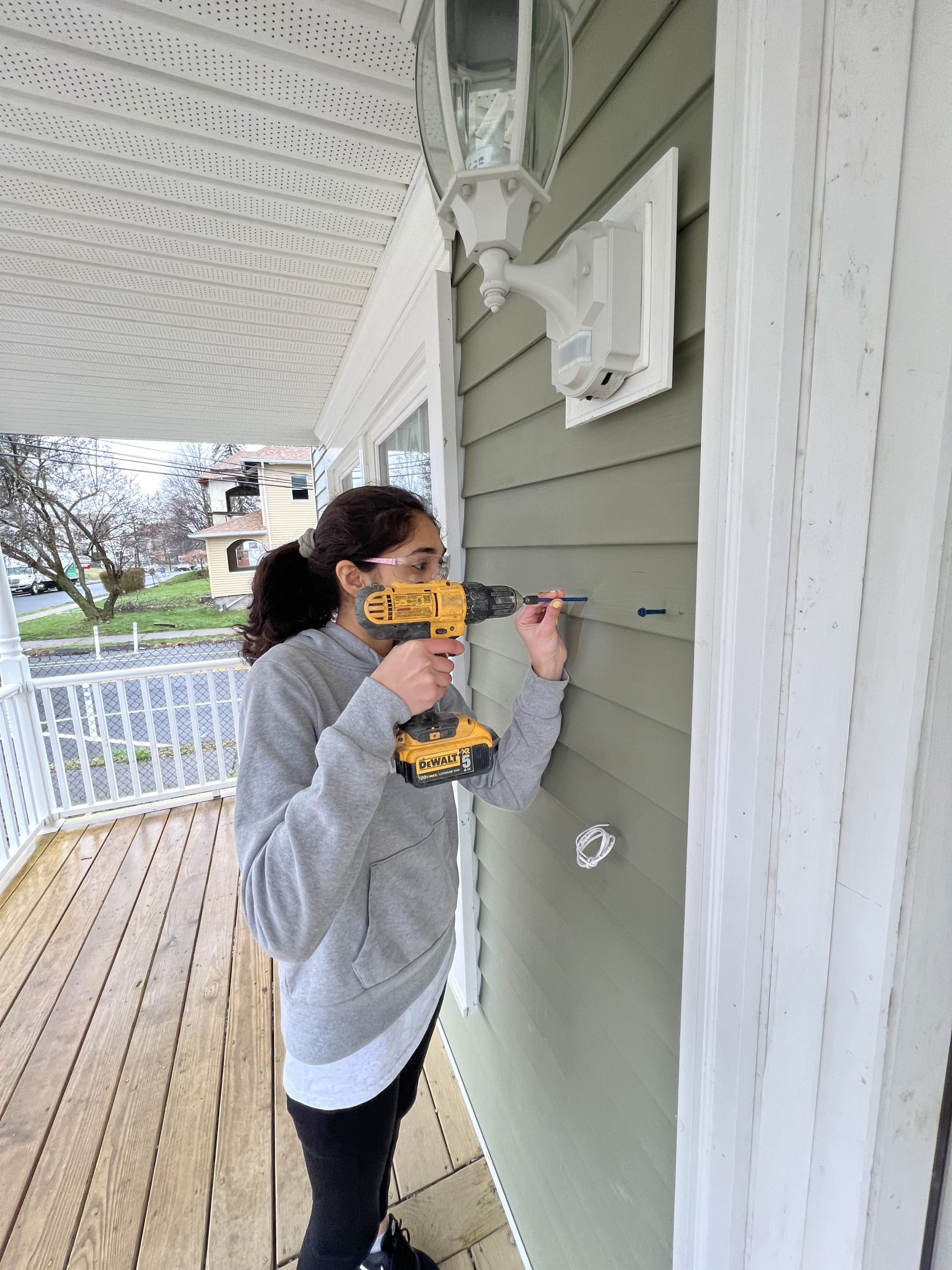 Diya Makadia, sophomore, drilling into the facade of home in order to mount a mailbox.